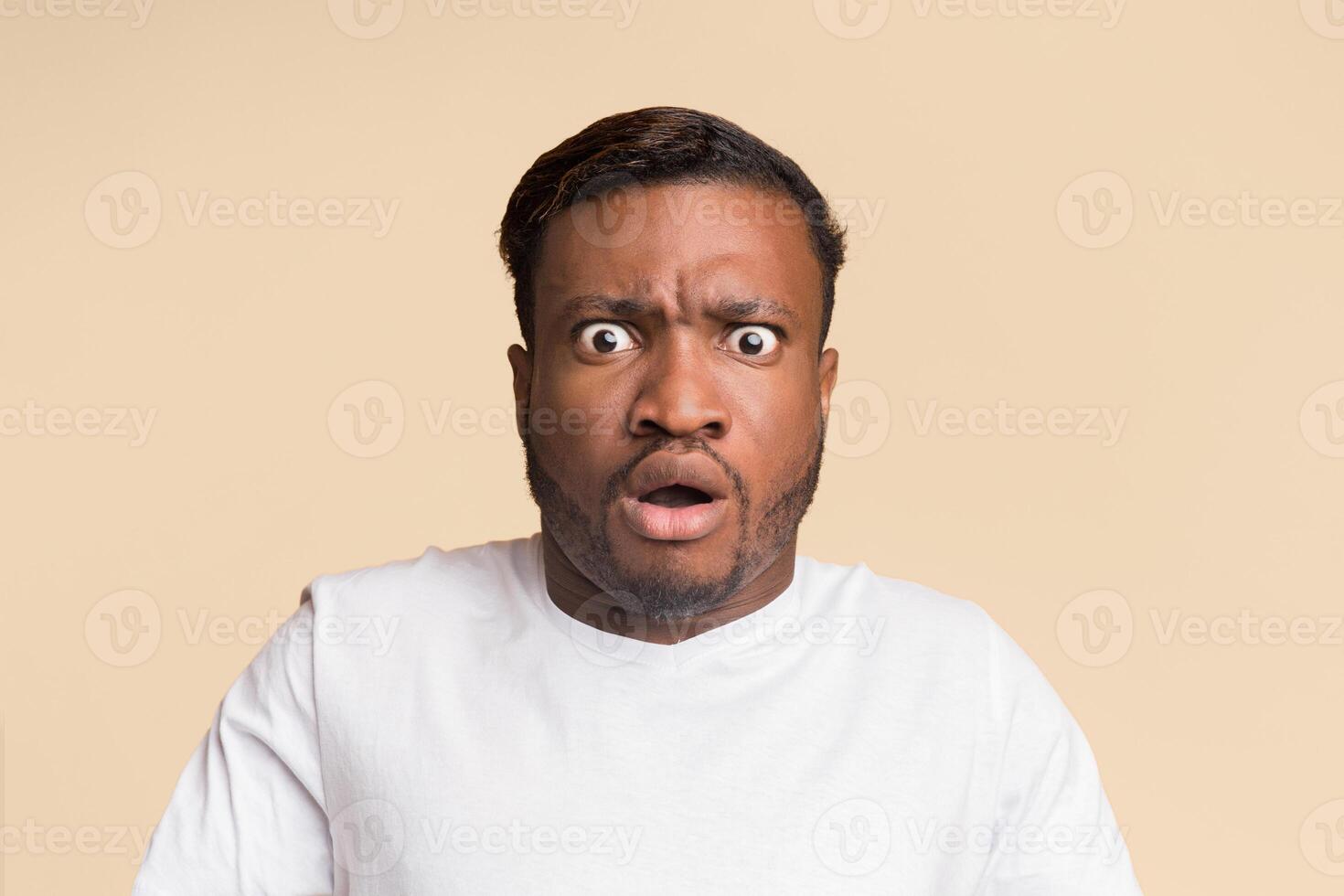 Shocked Afro Man With Opened Mouth Looking At Camera Standing On Yellow Background. Studio Shot photo