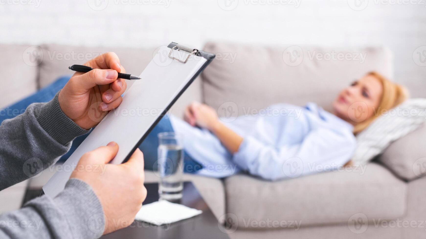 Mental health and counseling concept. Psychologist listening to depressed female patient and writing down notes, panorama photo