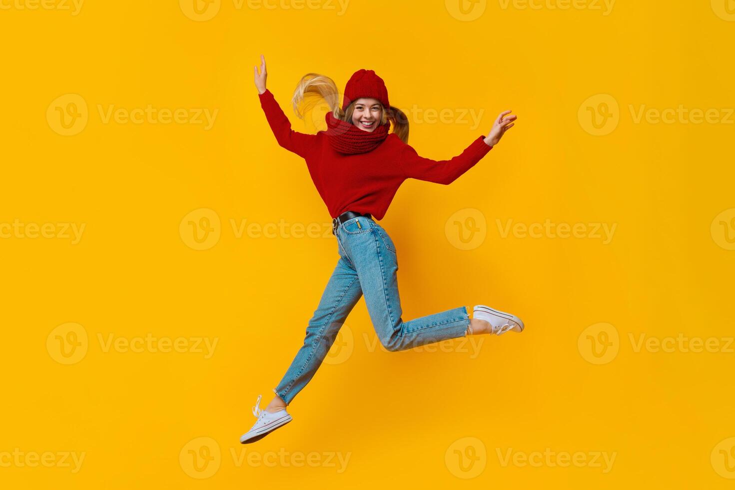 Cheery blonde winter girl having fun over yellow studio background photo