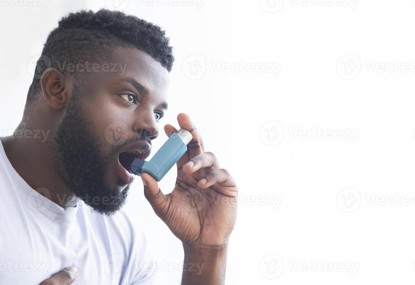 Young african man using asthma inhaler at home. Modern generation sickness, empty space photo