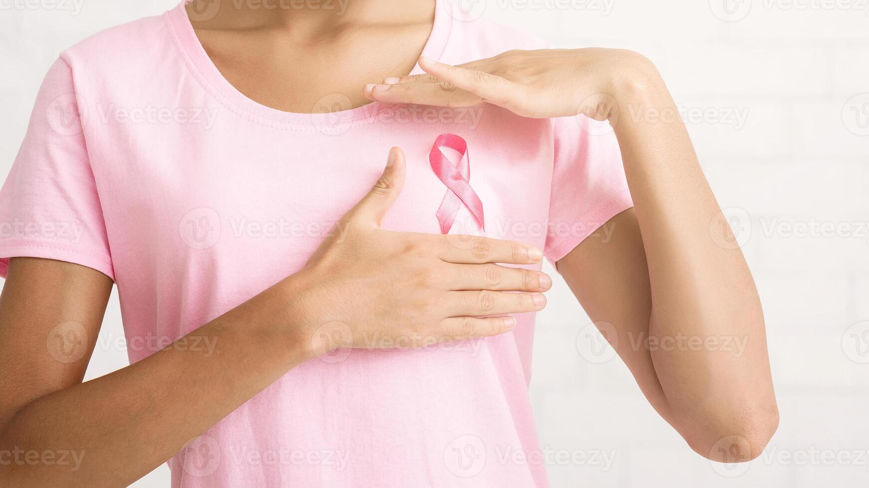 Breast Cancer Concept. Afro Girl In Pink Ribbon T-Shirt Posing Over White Brick Wall Indoor. Free Space For Text photo