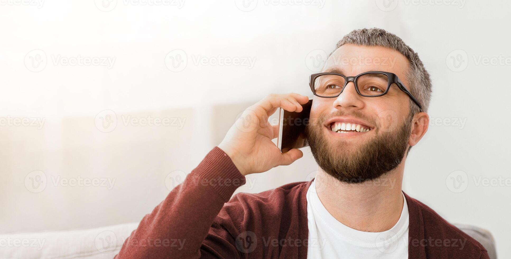 A man wearing glasses is engaged in a conversation on his cell phone, holding it to his ear. He appears focused and attentive as he communicates with the other party. photo