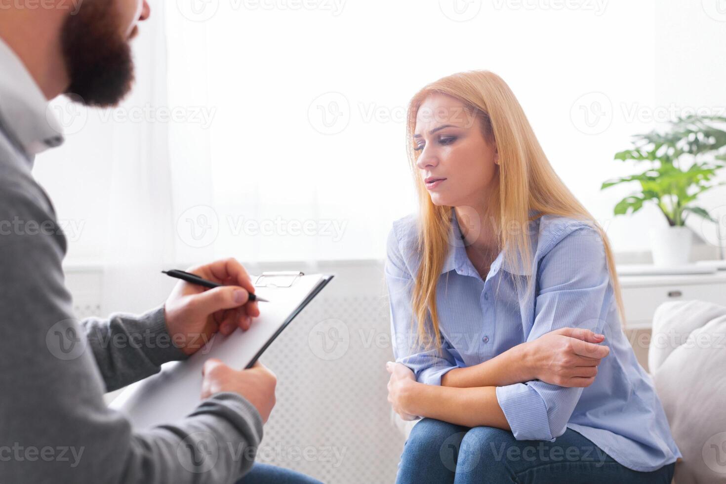 Psychotherapy. Depressed millennial woman sharing her problems with psychologist at personal session, empty space photo
