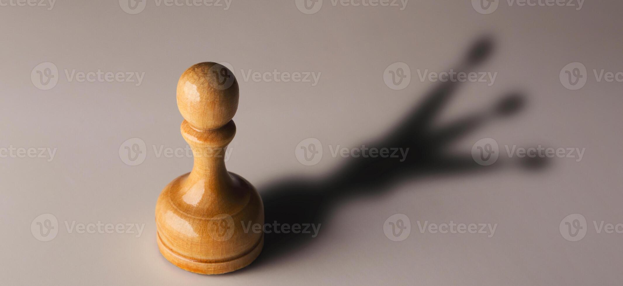 Trust yourself, self confidence concept. Wooden chess pawn with king shadow on gray background, motivation poster photo