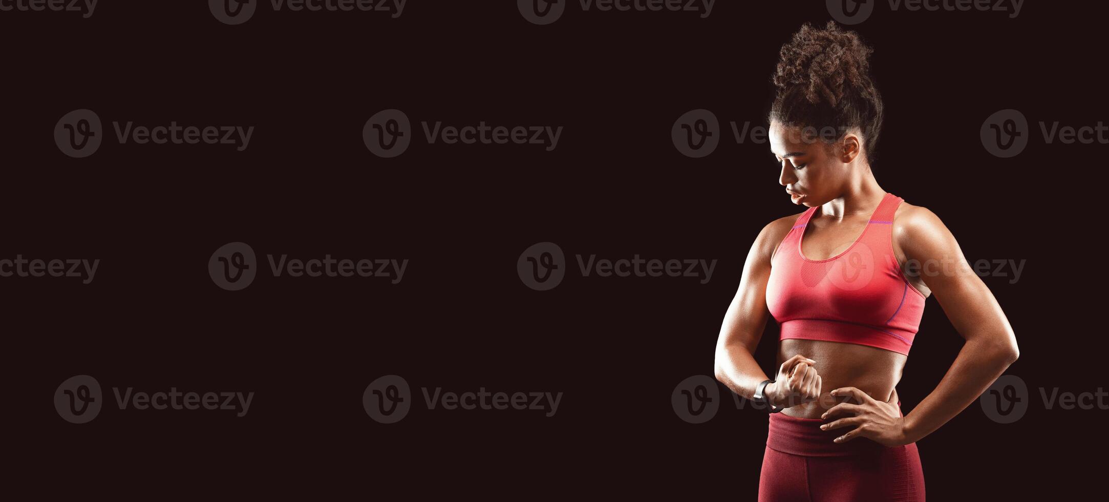 African girl bodybuilder showing muscular biceps, black studio background, free space photo
