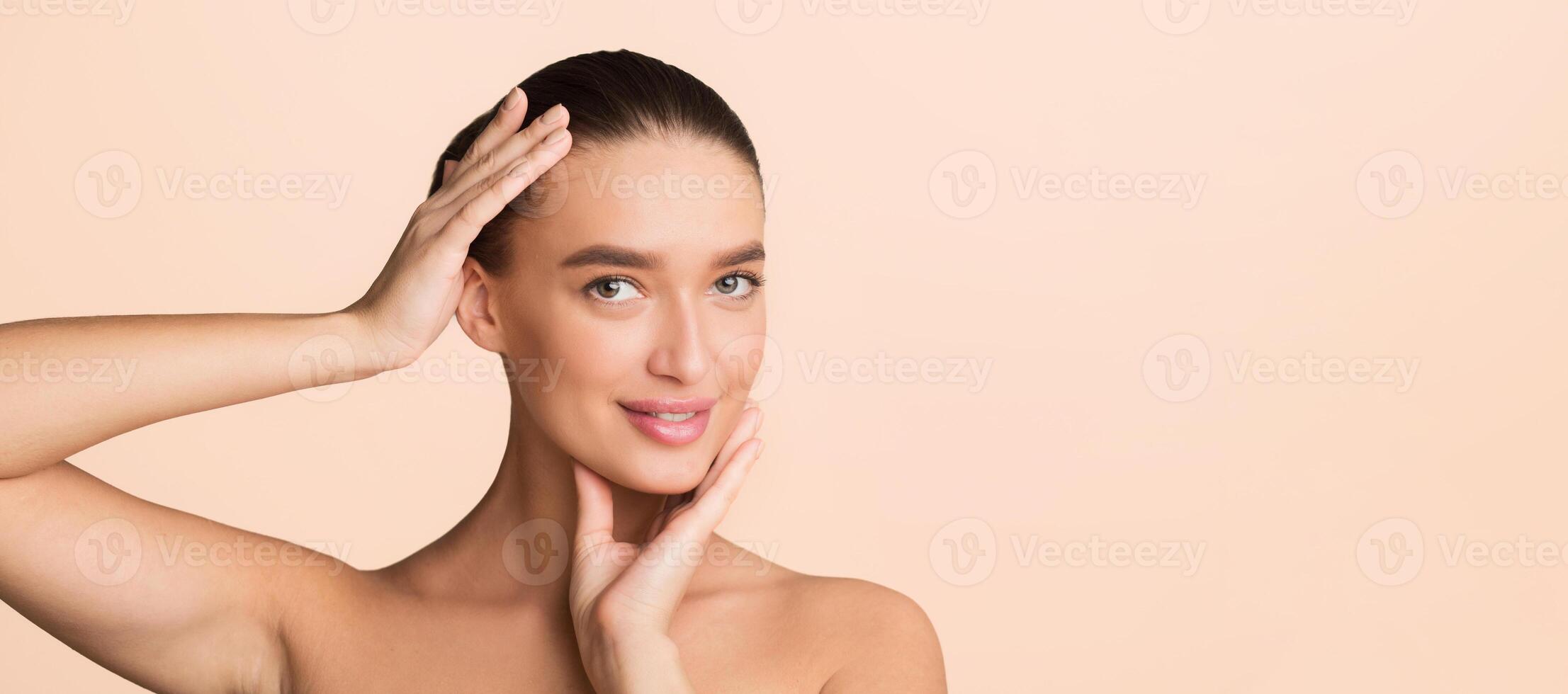 A woman stands with her hands pressed against her cheeks, adding a dramatic effect to her pose. She looks directly at the camera, showcasing a sense of contemplation or surprise. copy space photo