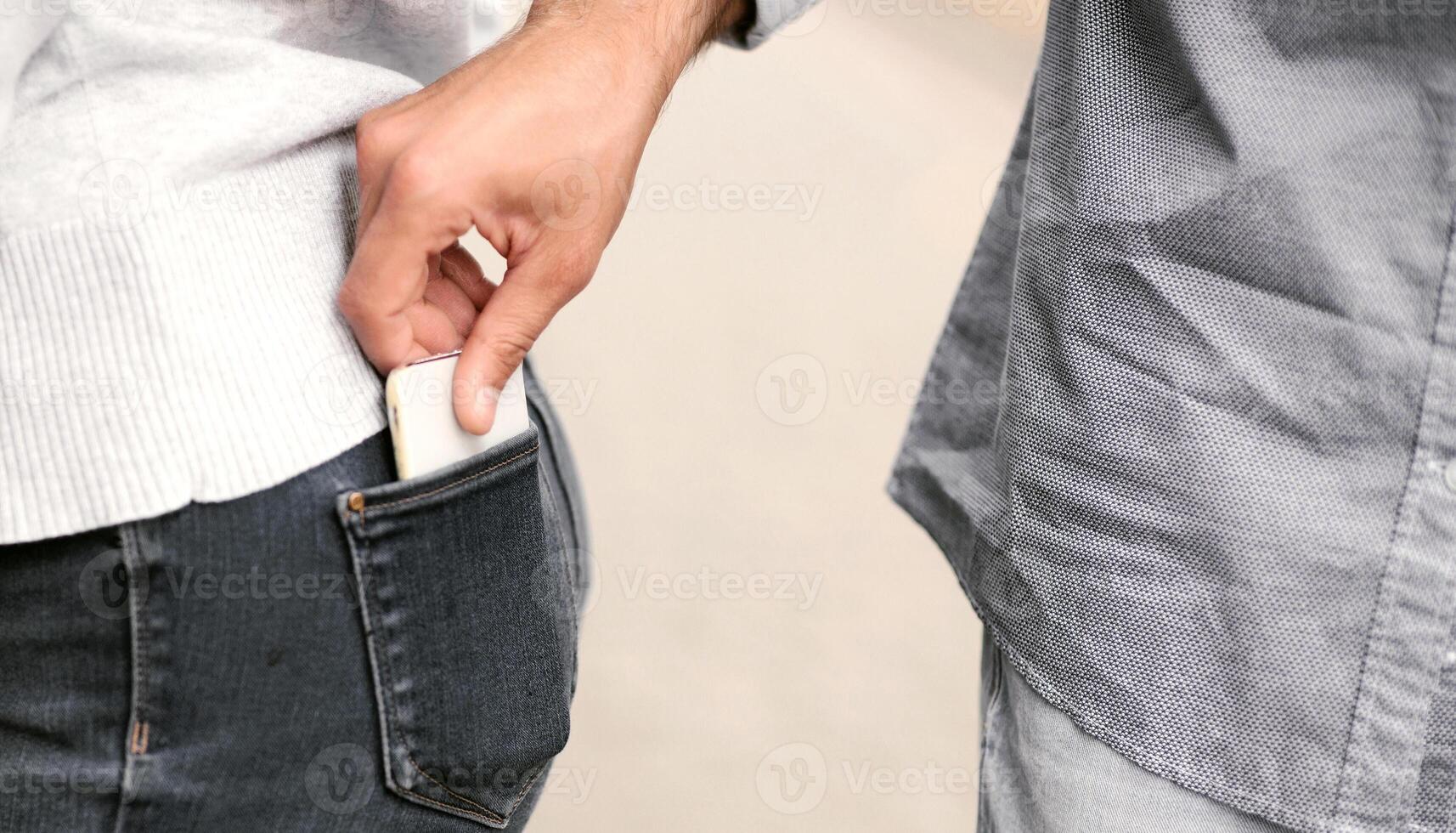 Pickpocketing. Thief Stealing Smartphone From Woman's Pocket On A Street In City. Cropped, Closeup photo