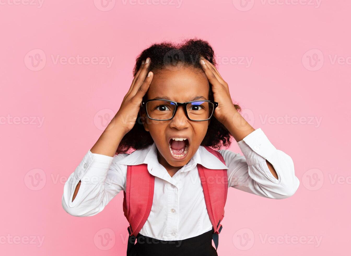Stressed Black Schoolgirl Shouting Touching Head Standing In Studio On Yellow Background. High-Angle, Vertical Shot photo