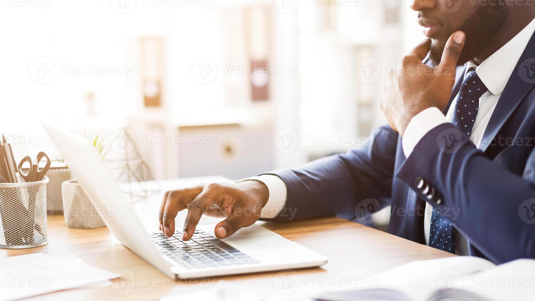Success and prosperity concept. African concentrated man in suit working with laptop, cropped, panorama with empty space photo