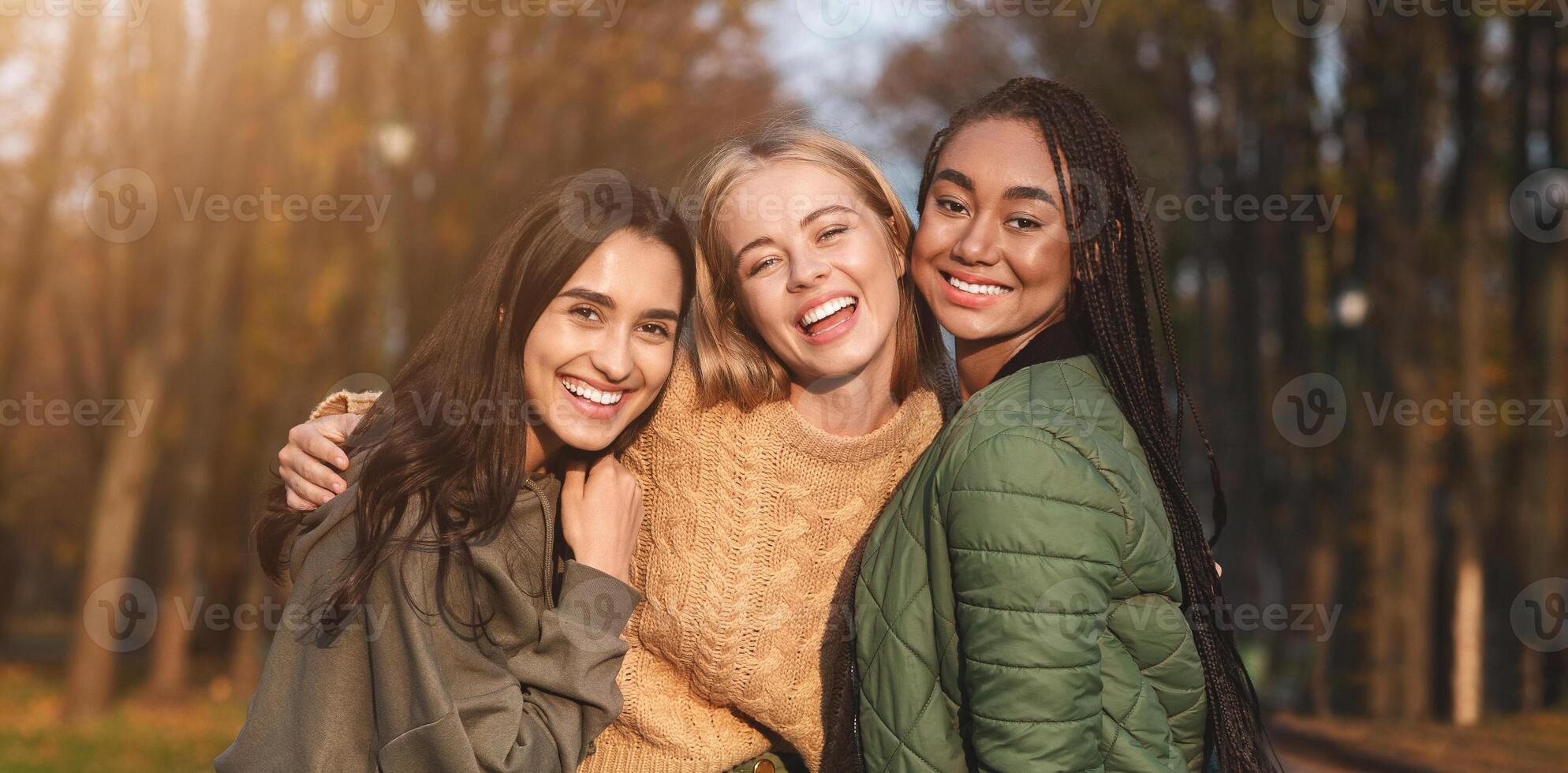 Portrait of three international young girlfriends spending time in park, panorama photo