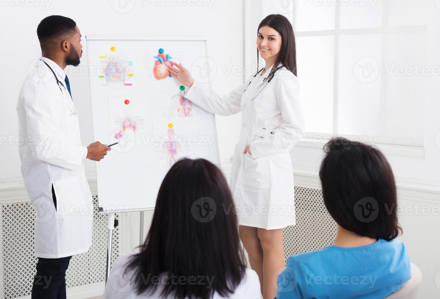 Sharing experience. Practitioners giving lecture to interns at medical seminar in hospital photo