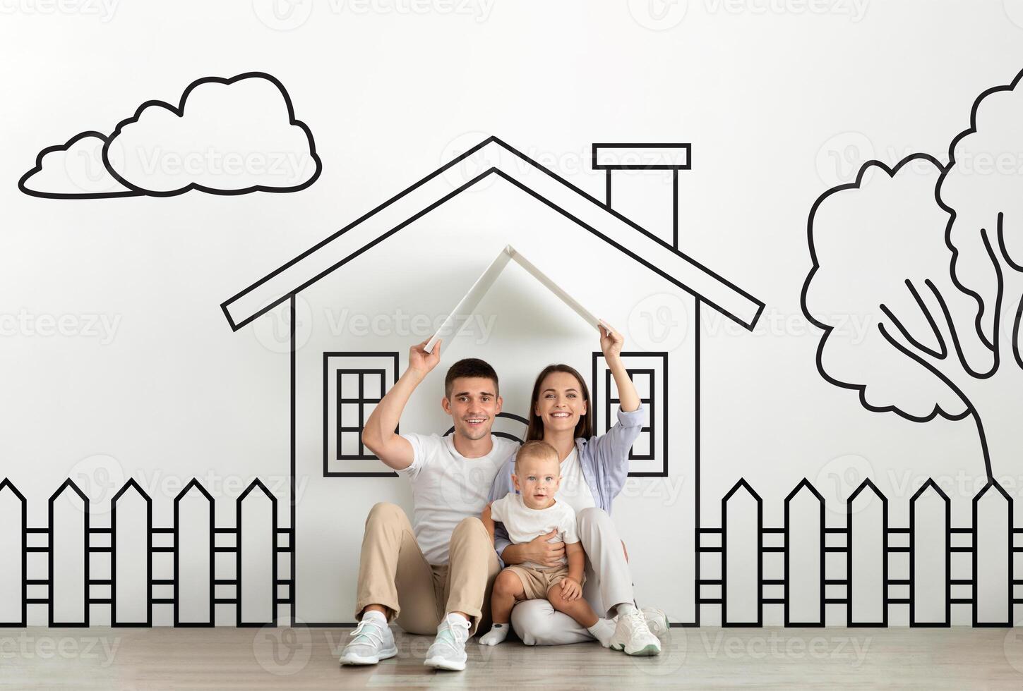 A family composed of parents and little baby is seated on the floor in front of a detailed drawing of a house. They seem engaged in discussing or admiring the artwork together in a home environment. photo