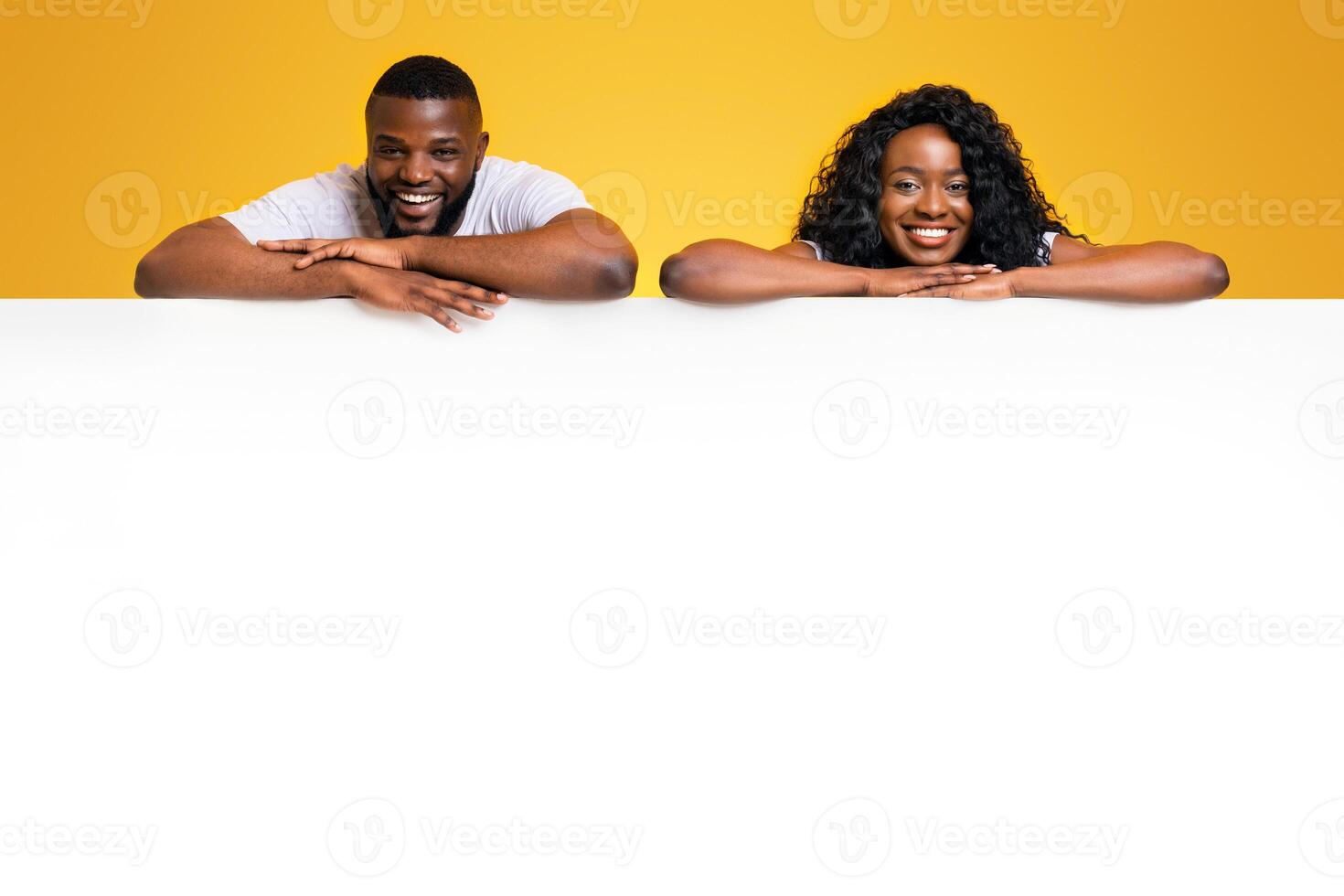 Free Space For Advertising. Afro couple is leaning on empty white board, yellow background photo
