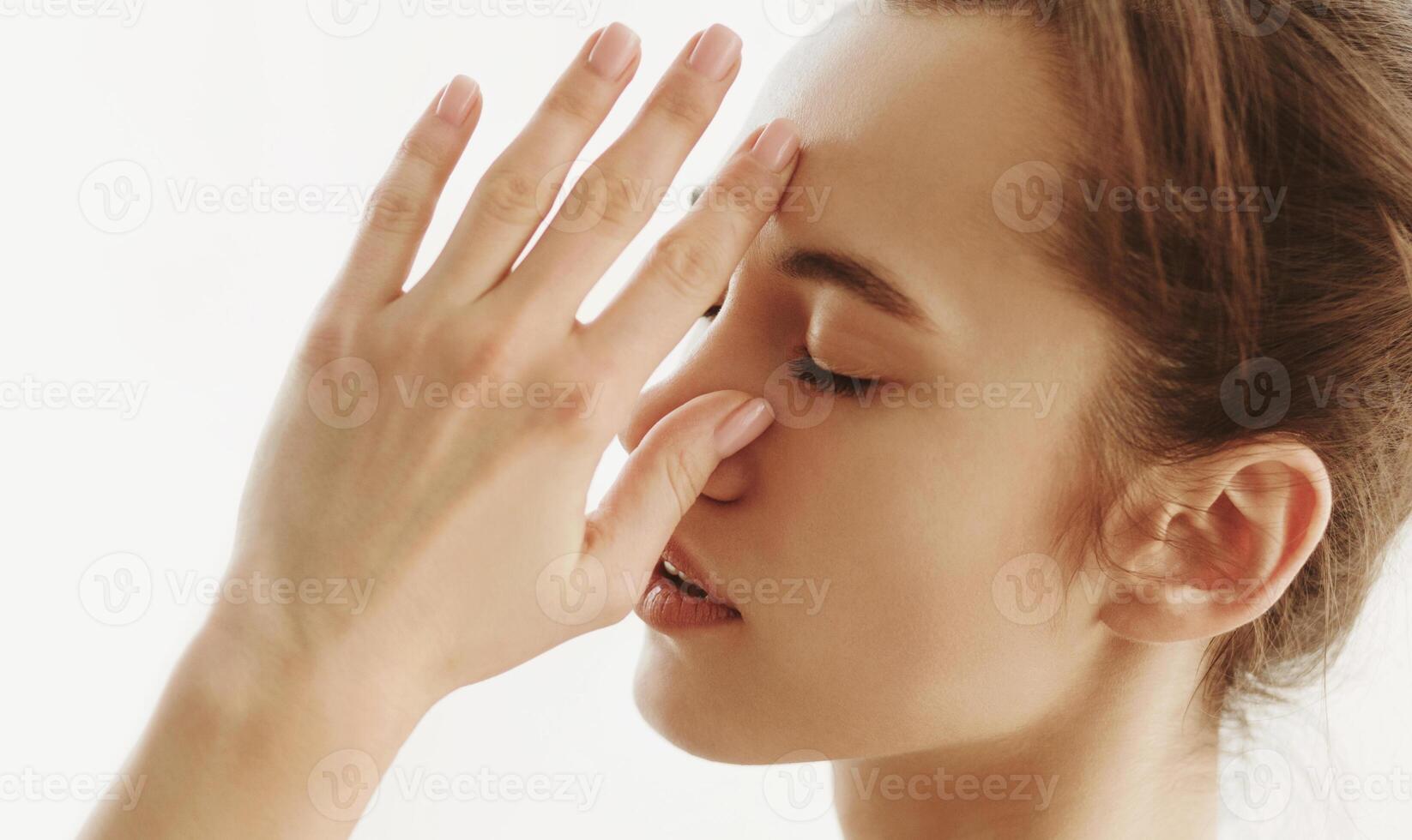 A woman is shown holding her hand up to her face in a gesture of contemplation or emotion. Her fingers are gently touching her forehead or chin as she looks pensive or deep in thought. photo