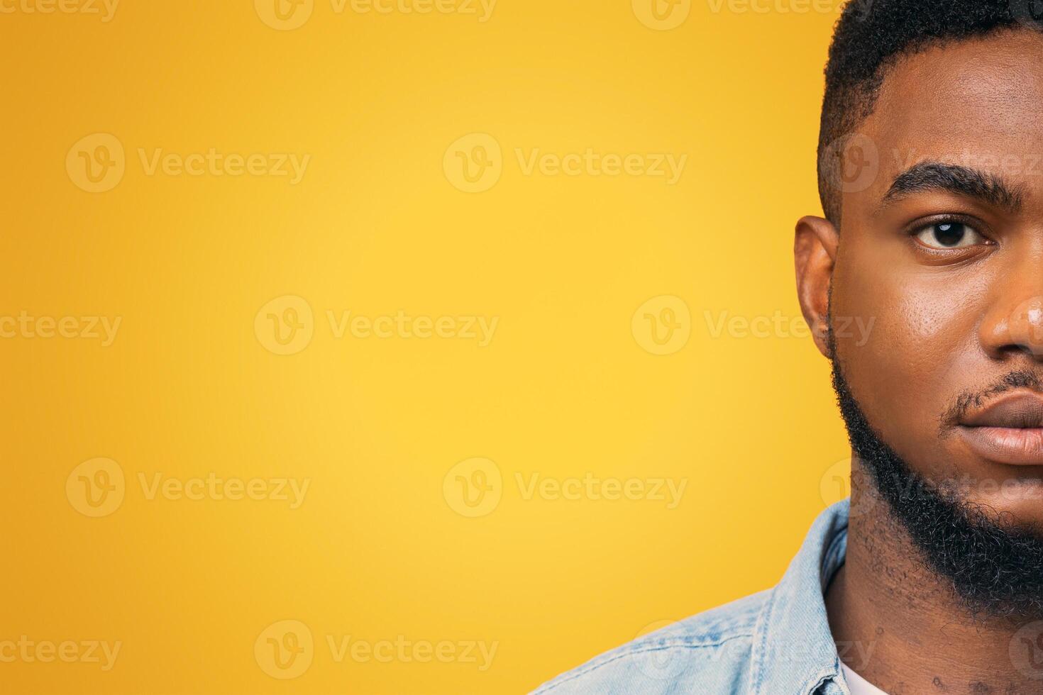 Half face portrait of confident african american man with beard on yellow studio background, free space photo