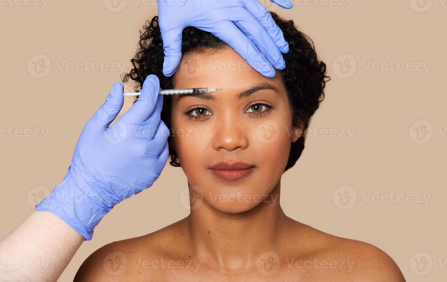 A woman is undergoing filler injection on her forehead. A healthcare professional is carefully administering the injection to reduce wrinkles and fine lines, closeup photo