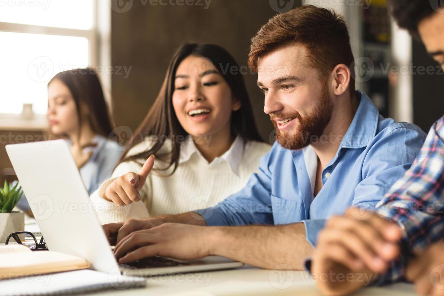 Smart college students networking on laptop in library, doing homework together photo