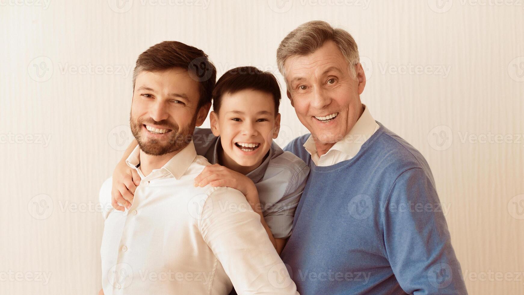 Male Family Portrait. Smiling Boy With Father And Grandfather Hugging Looking At Camera Standing Against White Background. Panorama photo