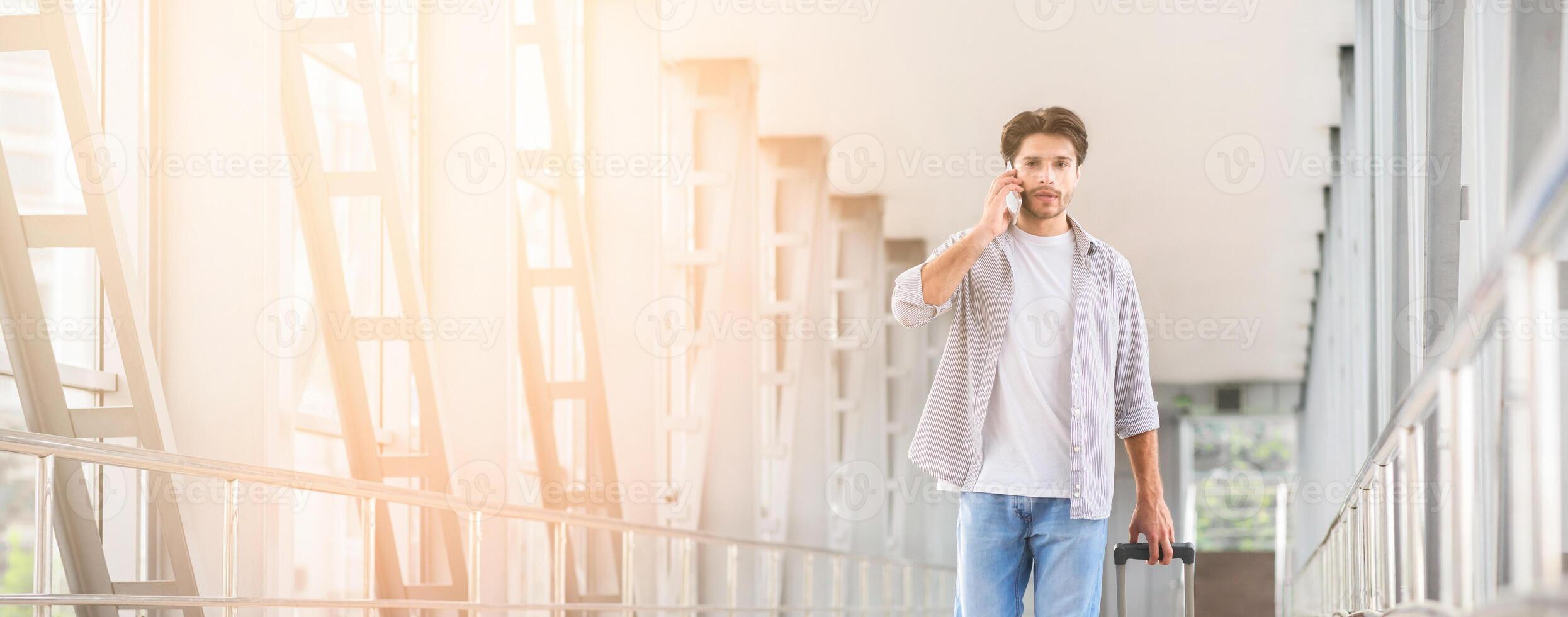 I Arrived. Young Man Walking With Suitcase In Airport Terminal And Talking On Cellphone, Caling To Family Or Taxi, Copy Space photo