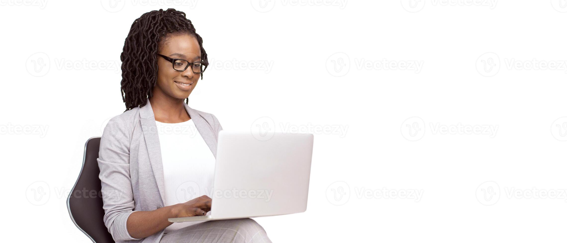 Black millennial businesswoman wearing eyeglasses using a laptop, isolated on a white background, panorama with copy space photo