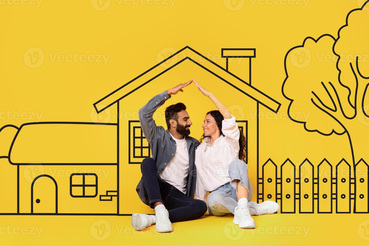Diverse man and a woman couple are sitting on the ground in front of a house. They appear relaxed and engaged in conversation, with the house as a backdrop. photo