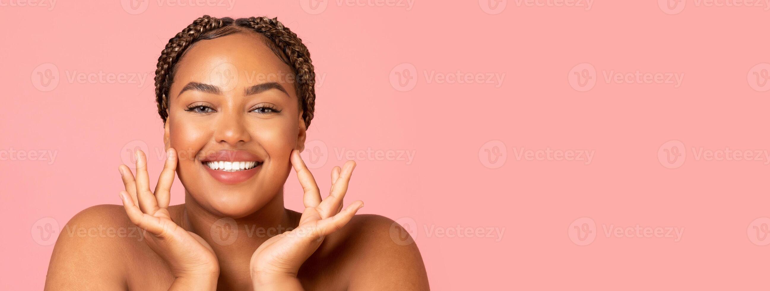 Facial Skincare. Attractive Black Woman Touching Face Moisturizing Smooth Skin Posing Smiling To Camera Over Pink Background In Studio. Beauty Routine And Pampering Concept, Copy Space photo