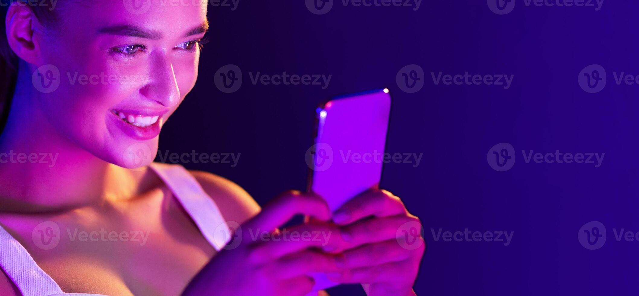 A woman is happily smiling while using a cell phone to communicate with someone. She is engaged in the conversation and appears content, panorama with copy space photo