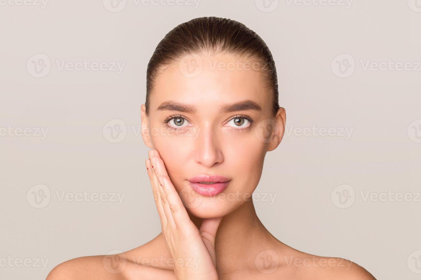 A woman is standing and posing with her hands placed on her face, creating a thoughtful or contemplative expression. She appears to be deep in thought or emotion, showcasing a moment of introspection. photo