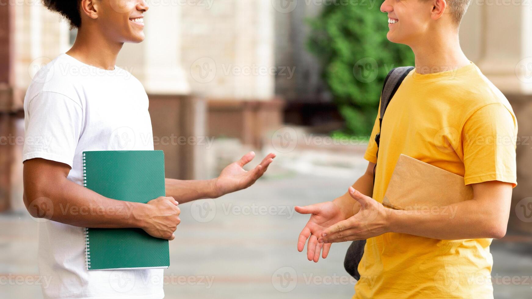 Cheerful students discussing something outdoors, having break in university campus photo