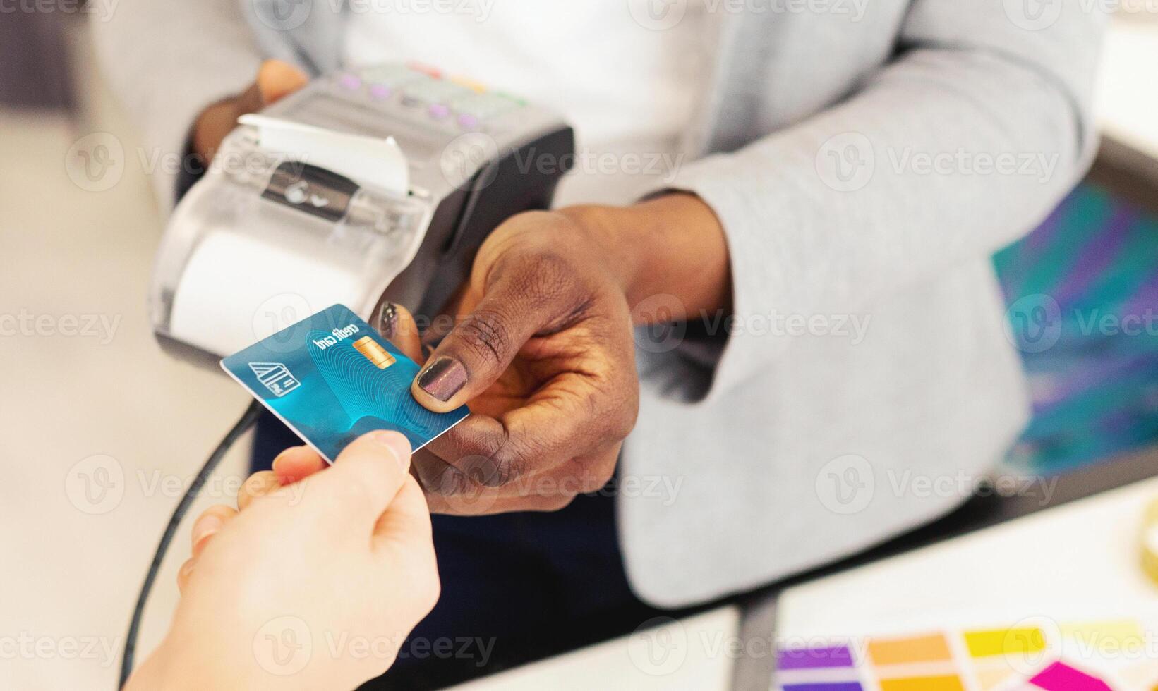 African American lady holding a credit card in her hand, showing the front side with a chip and embossed numbers. The background is a simple, neutral color to give focus to the card. photo