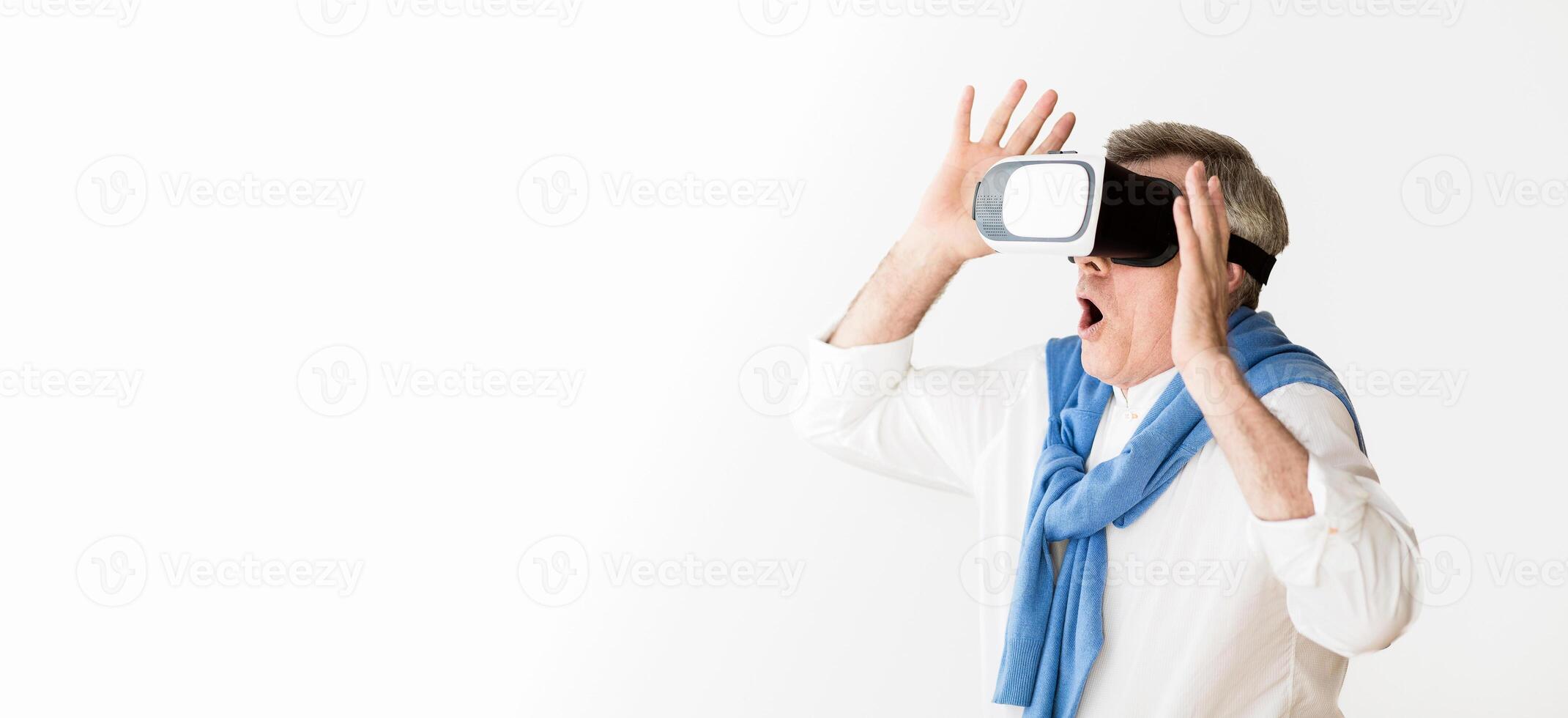 VR world. Mature man enjoying futuristic technologies with virtual reality glasses at home photo