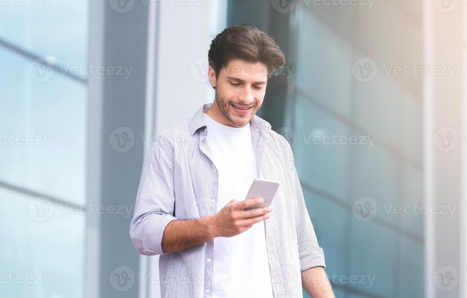 Ordering Taxi. Millennial Guy Using Smartphone While Standing With Suitcase Near Airport, Relaxing Outdoors After Flight, Free Space photo