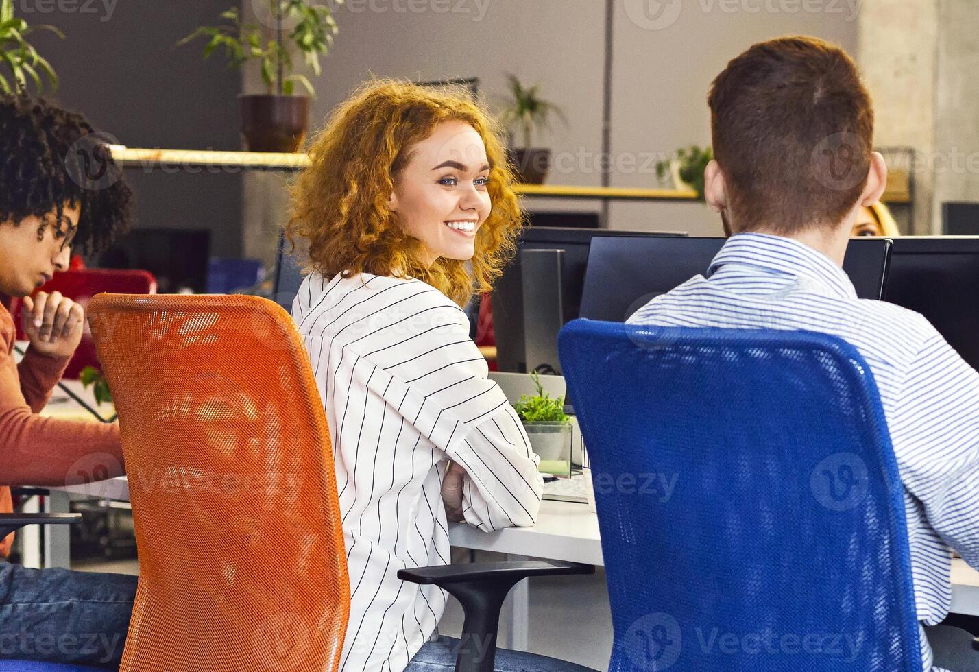 Man and woman seated around a table, all engaged in using computers. They are focused on their screens, possibly working on a project or discussing ideas, have conversation photo