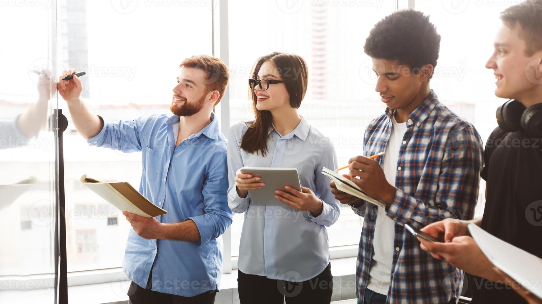 Male student writing on whiteboard in classroom, classmates taking notes during class workshop photo