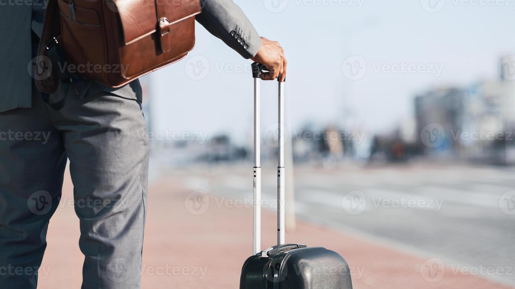 Cropped of businessman is walking with his luggage outside a modern airport. The mood is dynamic and professional, highlighting travel and business with a sleek airport backdrop. photo