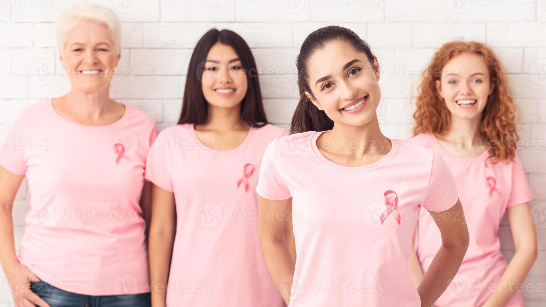 Indian Woman Standing With Breast Cancer Volunteers Group Smiling To Camera Over White Background. Selective Focus photo