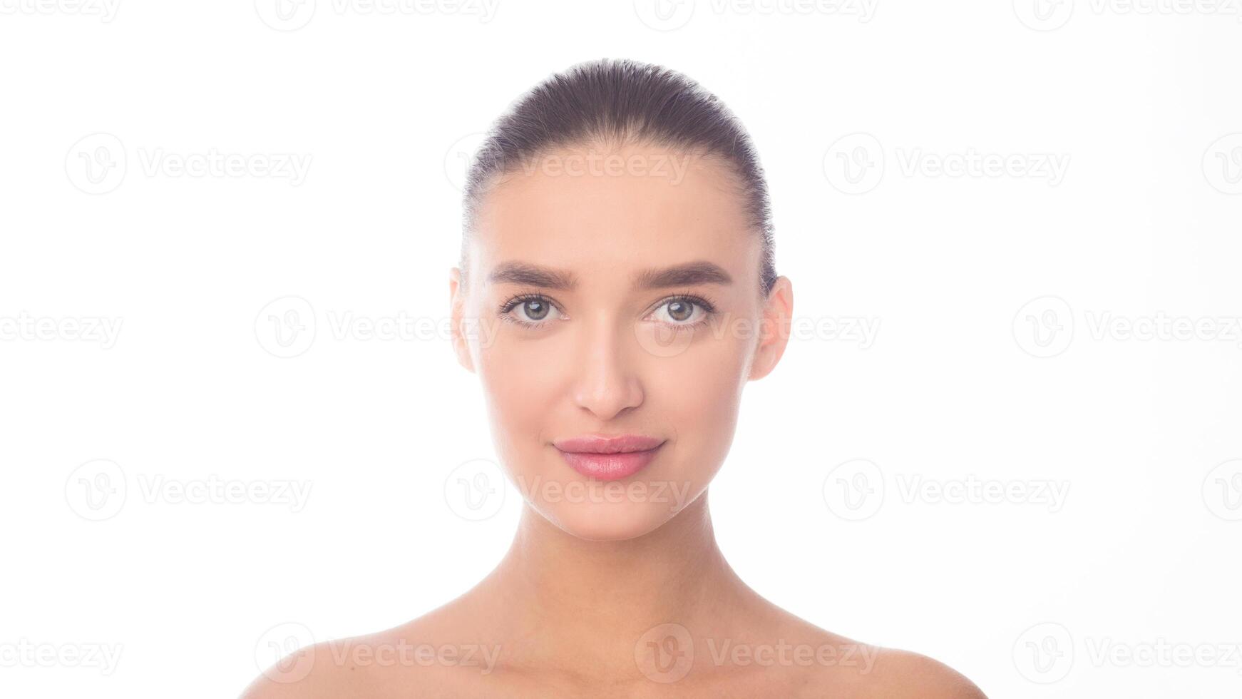 A close-up view of a woman face against a plain white background. Her features are visible, including her eyes, nose, mouth, and hair. The woman appears calm and composed in the photo. photo