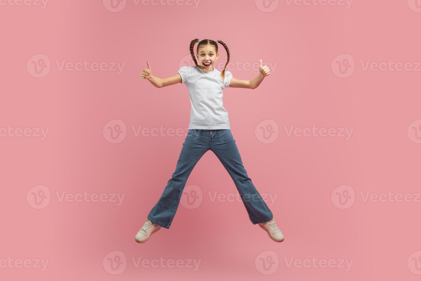 A young girl child is joyfully leaping into the air with her arms outstretched. She appears to be full of energy and excitement as she jumps high off the ground. photo
