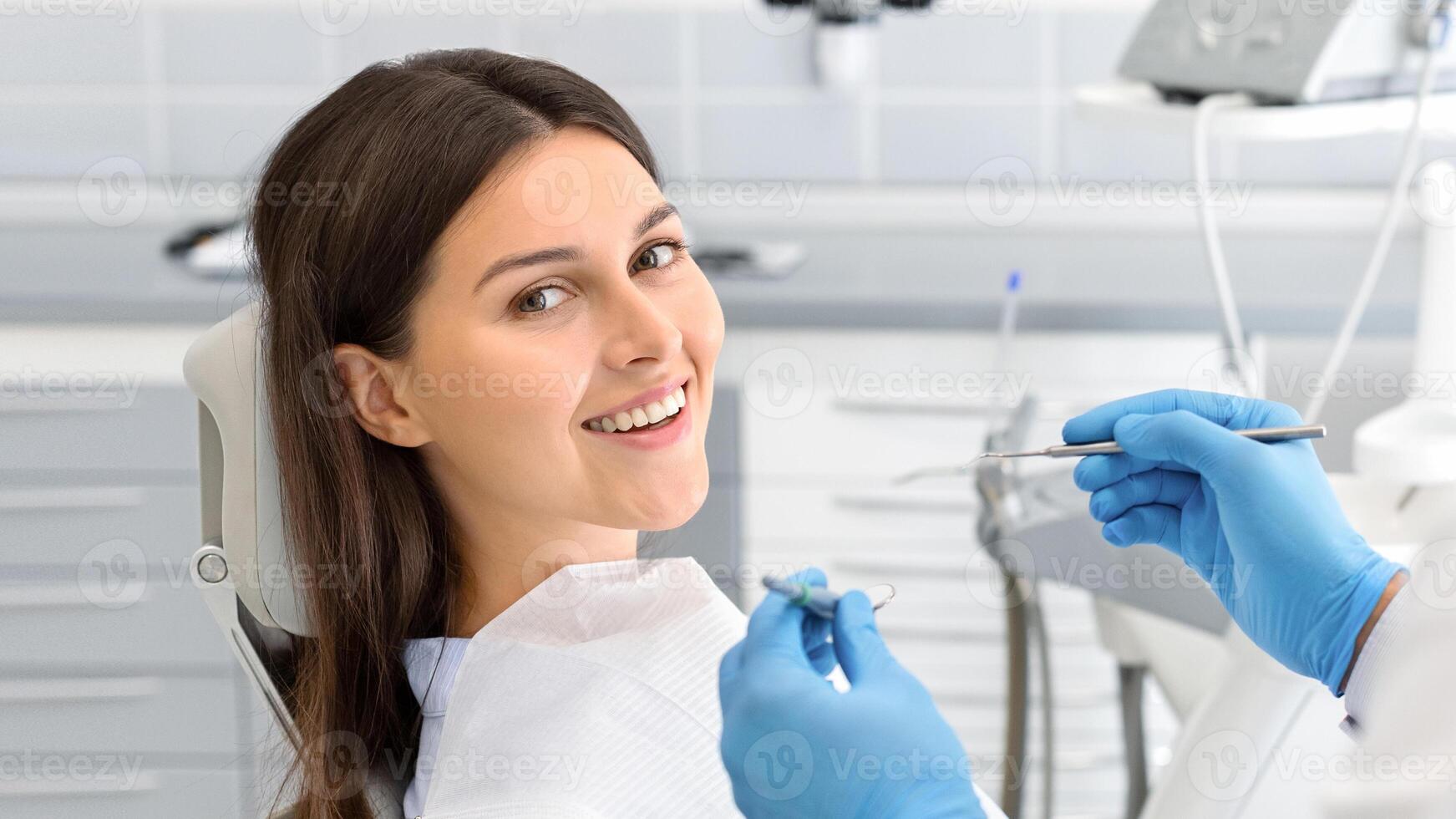 Young happy lady sitting in dentist chair, making regular check up in modern clinic, close up, free space photo