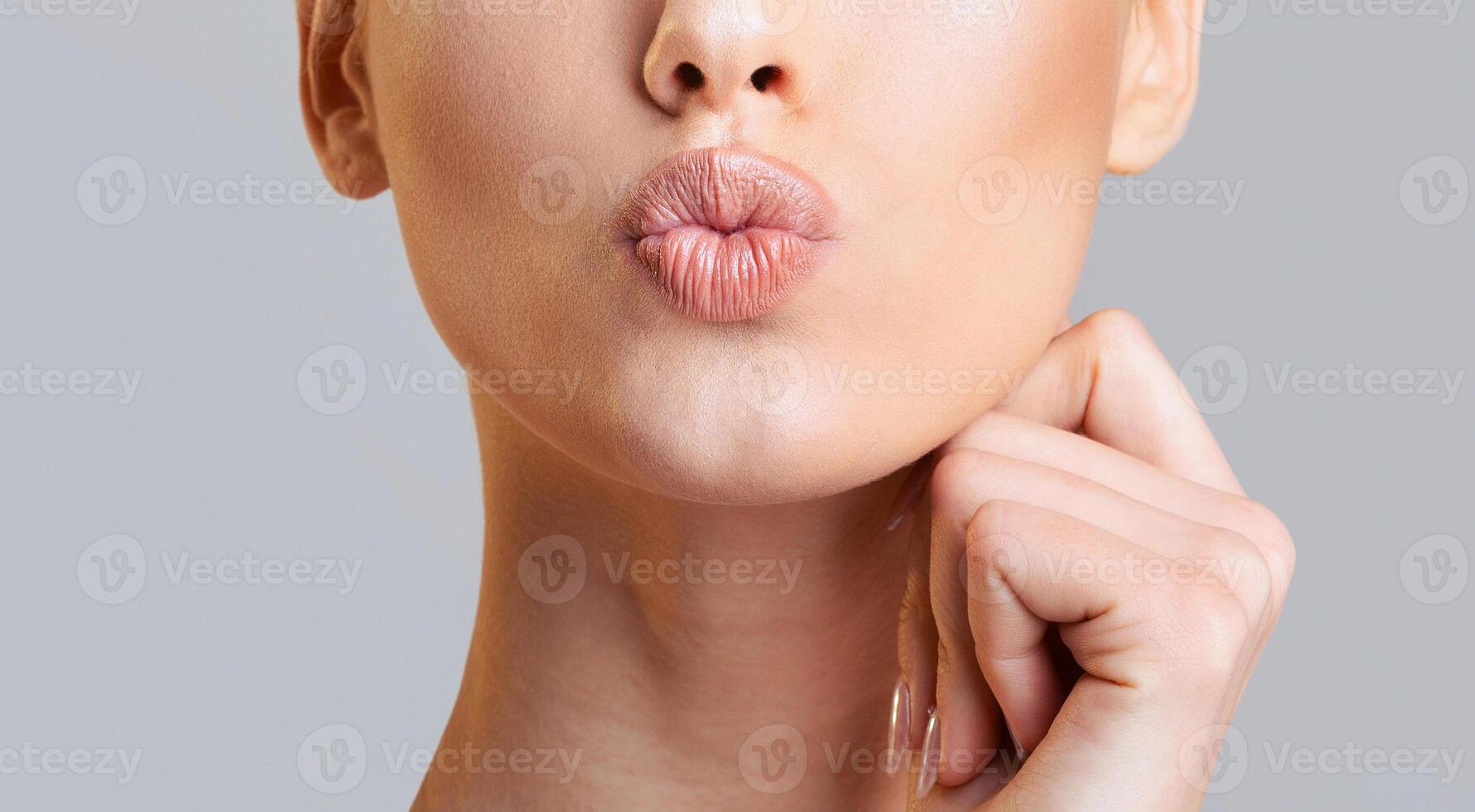 Cropped of woman face, showcasing her lips as they pout in a slightly seductive expression. She has a hand resting on her chin, adding a touch of sensuality to the overall pose, cropped photo