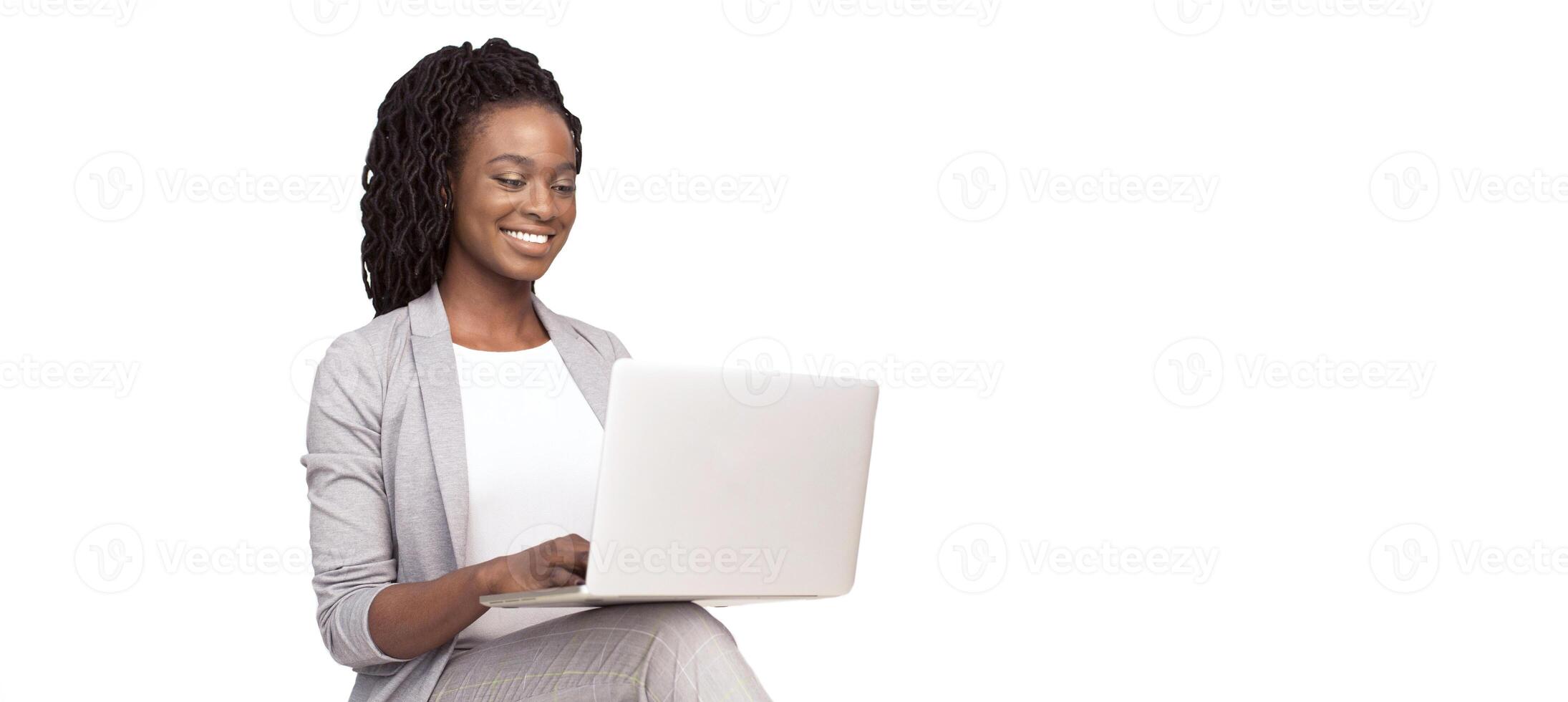 Smiling African American millennial businesswoman using a laptop, isolated on a white background, panorama with copy space photo