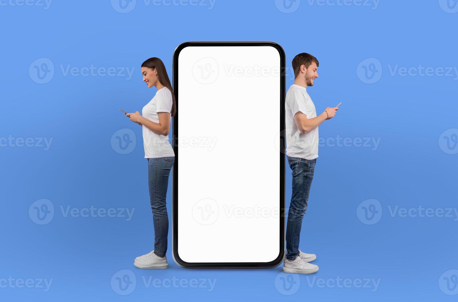 A man and woman are standing next to a large screen phone, appearing to be engaged in a conversation or viewing content on the device. Both individuals seem focused on the screen in front of them. photo