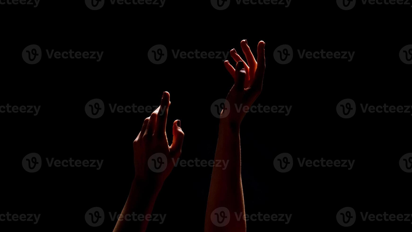 This image shows two hands reaching upwards towards the unseen, illuminated by an unknown light source. The hands are silhouetted against a dark background, cropped photo