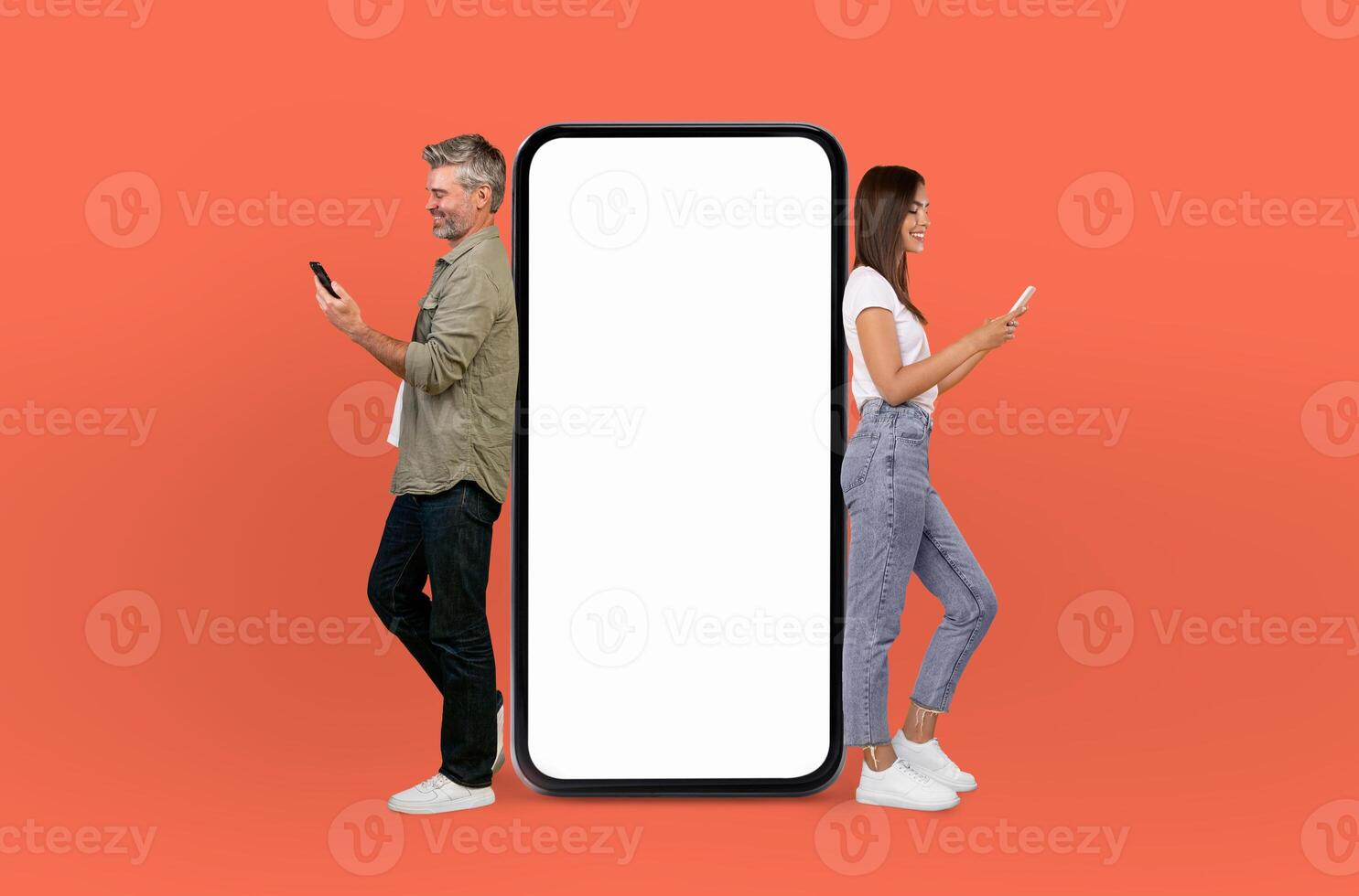 Energetically, the middle aged couple engages with viewers, standing next to a mockup smartphone that offers a clear, unoccupied screen for various displays. photo