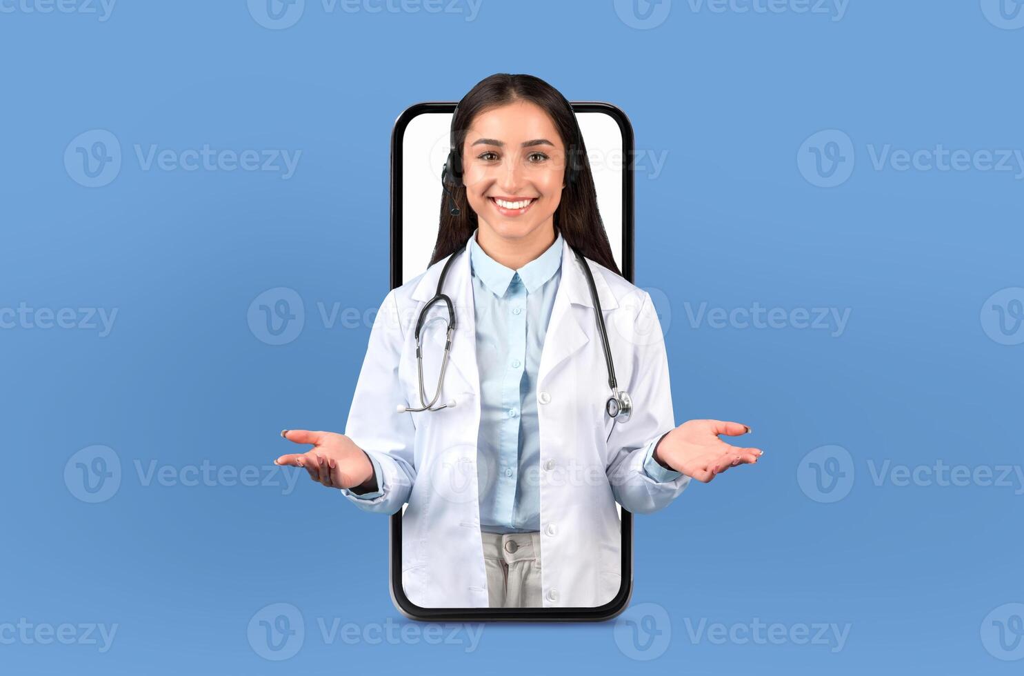 A woman wearing a white coat is standing in front of a telephone. She appears to be interacting with the phone, possibly making a call or sending a message. photo