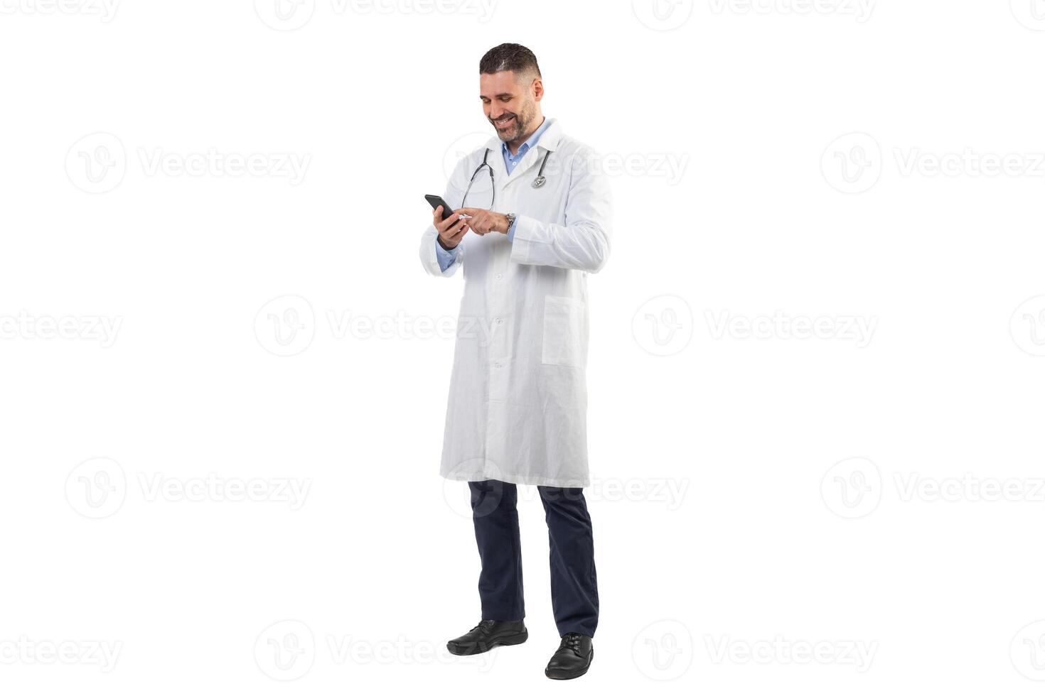 A man doctor dressed in a white lab coat, with a stethoscope around his neck, checks messages on his smartphone during daylight hours on his hospital shift. photo