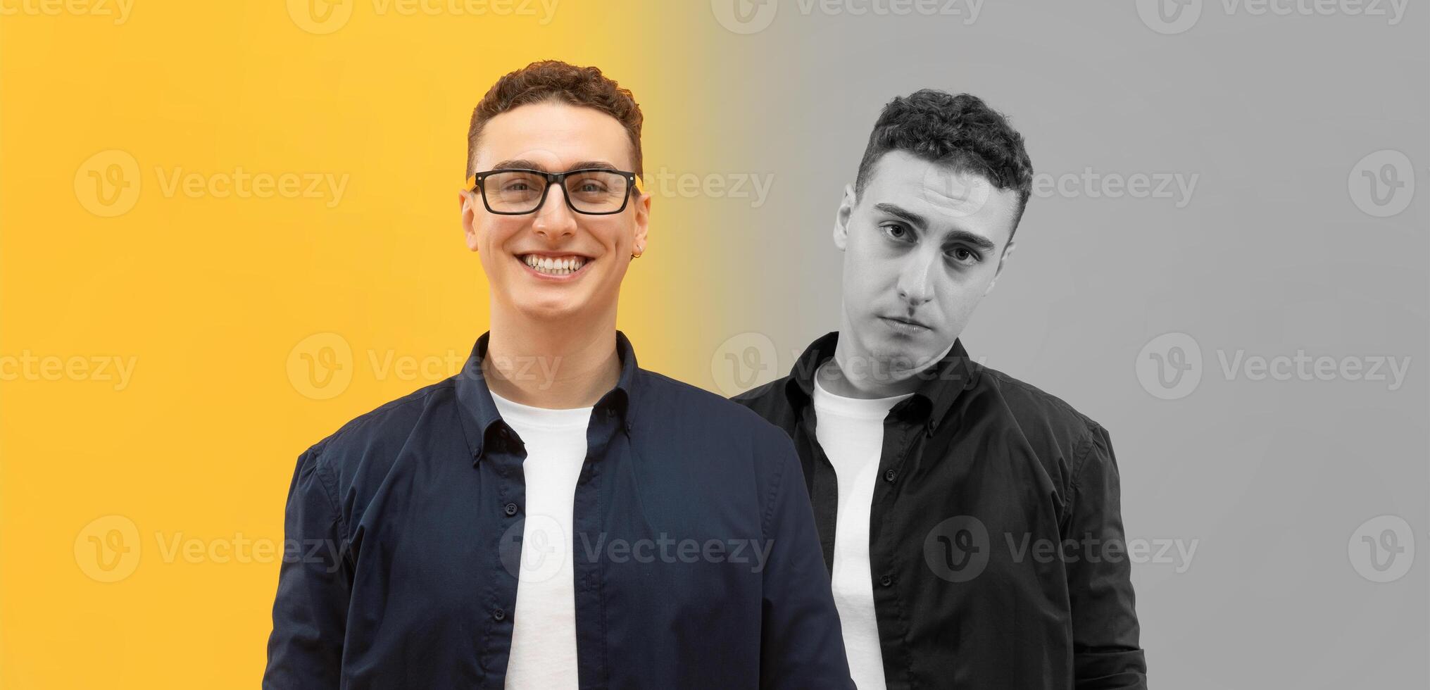 One man stands cheerfully smiling while the other displays a serious expression, creating a striking contrast. They are positioned against a vivid yellow and muted gray backdrop photo