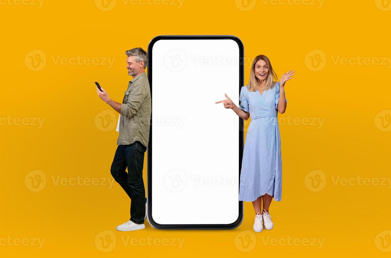 Mature man and woman are standing together next to a huge telephone, appearing to be engaged in a conversation or perhaps waiting for a call photo