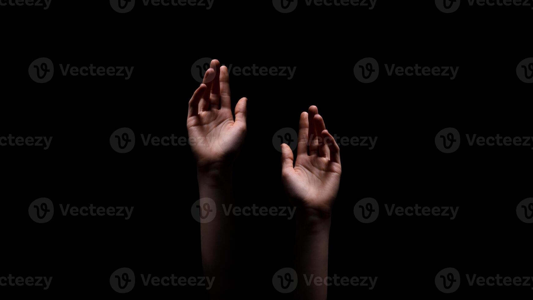 Two hands reaching up towards the dark, unknown, or possibly a source of light, suggesting a sense of hope or desperation, appear to be reaching out for something. photo