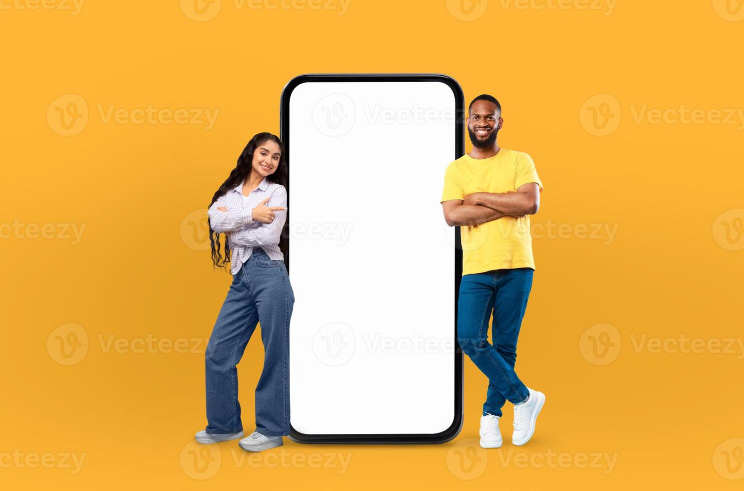 A man and a woman are standing next to a phone with a blank screen. They appear to be looking at the screen, possibly waiting for a call or message. photo